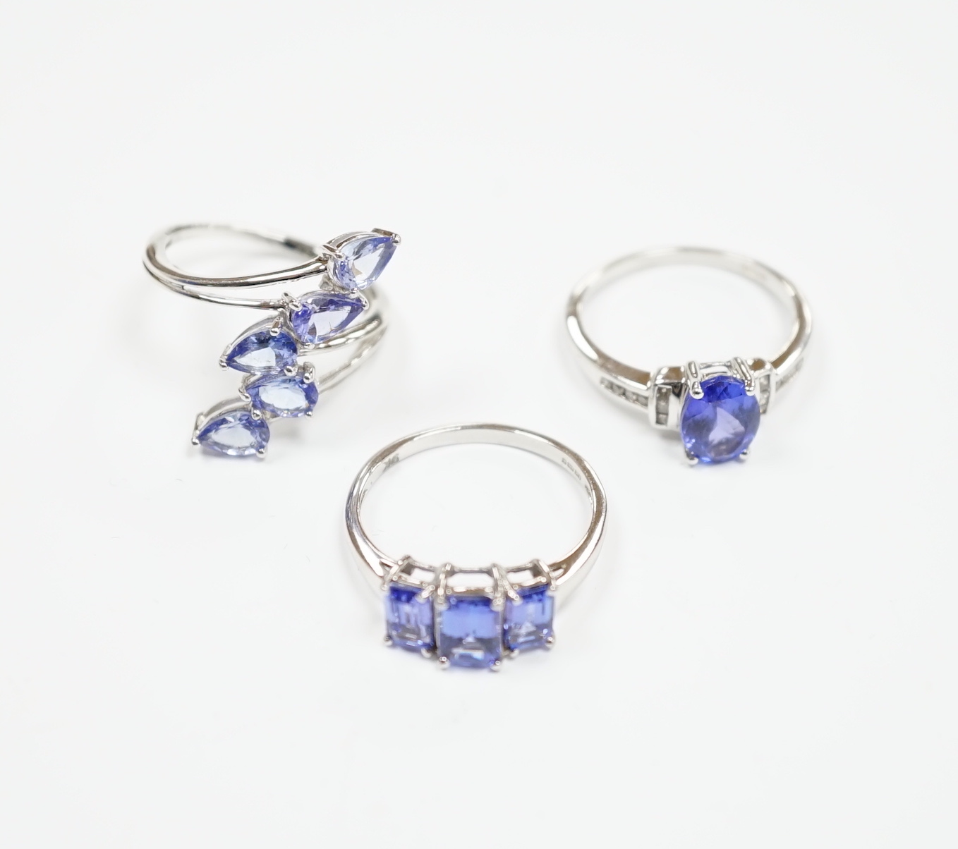 Three assorted modern 9ct white gold and tanzanite set dress rings, gross weight 8.4 grams.